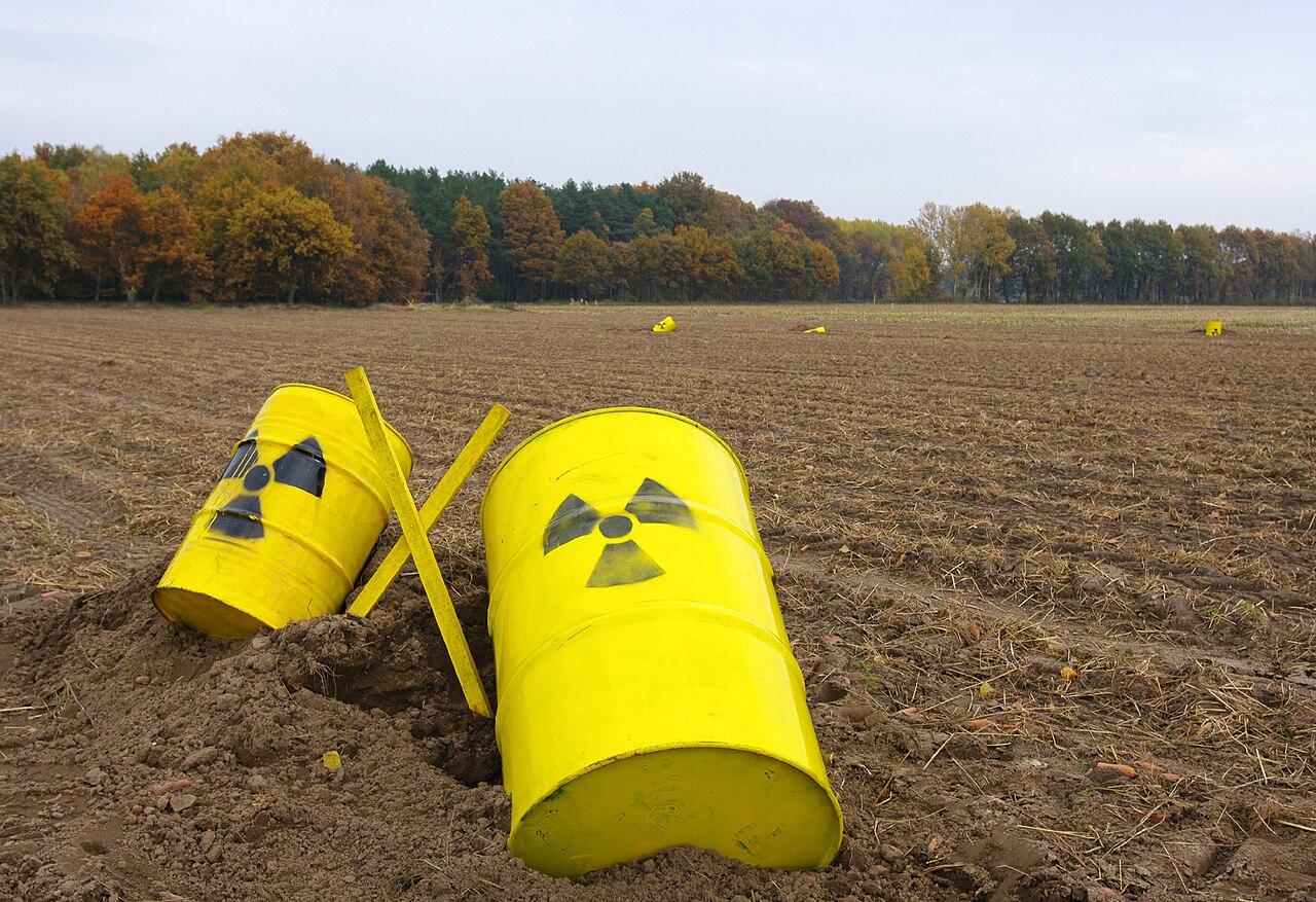 Yellow drums marked with radiation symbol in a field (illustrative)